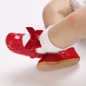 Dettaglio di scarpine rosse da principessa per neonata con fiocco di velluto.