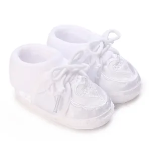 Detailed view of white baby christening shoes with heart embroidery and soft sole