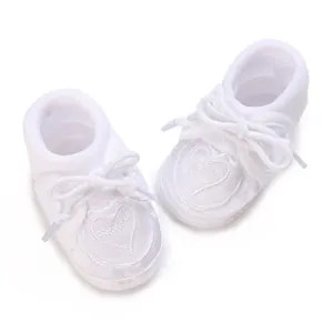 Detailed view of white soft-sole baby baptism shoes with embroidered heart pattern