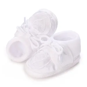 Close-up of white baby christening shoes with detailed heart embroidery and soft texture.