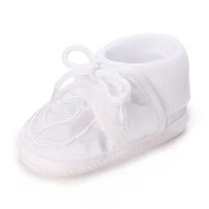 Vue détaillée d'une chaussure de baptême blanche pour bébé avec broderie en cœur