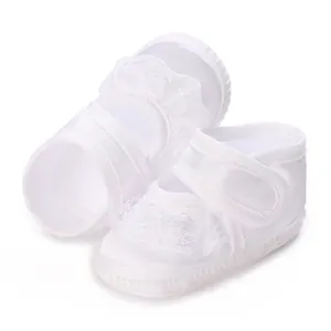 Detaillierte Nahaufnahme weißer Taufschuhe für Babys mit edler Spitze und Klettverschluss