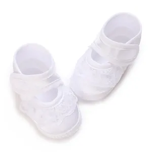 Detailansicht eleganter weißer Babyschuhe aus Satin für die Taufe mit feiner Spitze