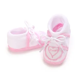 Close-up of pink and white baby floor socks with heart embroidery and white laces.