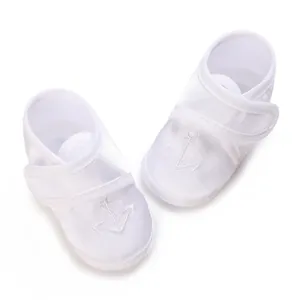 Close-up of white baby christening shoes with elegant anchor embroidery detail