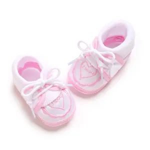 Close-up detail of soft pink infant floor socks with embroidered heart pattern and bow