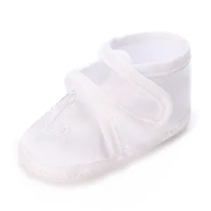 Gros plan d'une chaussure de baptême blanche pour bébé en satin avec broderie d'ancre