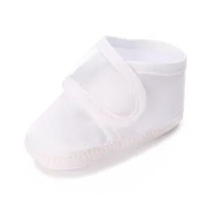 Gros plan d'une chaussure de baptême pour bébé en satin blanc avec velcro