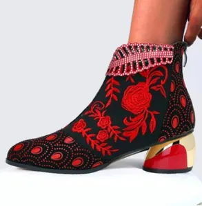 Détail de la broderie rose rouge et du talon doré sur une bottine noire ethnique