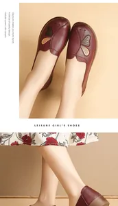 Detailed view of dark red leather flat shoes with butterfly embroidery on model feet