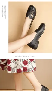 Close-up of black leather loafers with butterfly embroidery on beige background