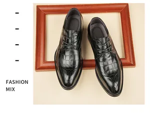 Top view of black crocodile-embossed leather brogue shoes in a wooden frame