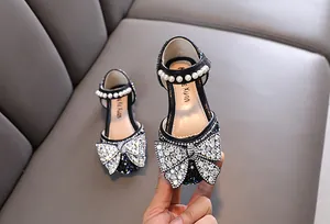 Primer plano de zapatos de princesa negros para niña con gran lazo de diamantes
