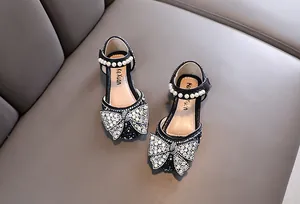 Vista detallada de los zapatos de princesa negros con lazo de diamantes y perlas