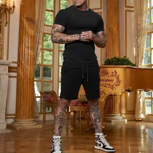 Uomo muscoloso con t-shirt nera e pantaloncini sportivi coordinati in una stanza di lusso