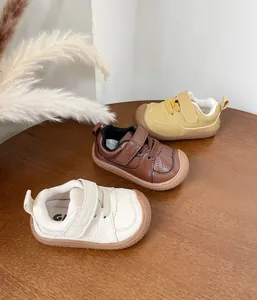 Detail view of toddler walking shoes in off-white, brown, and yellow soft leather
