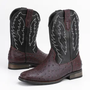 Détail de bottes de cowboy avec texture peau d'autruche et broderie flamme sur tige noire.