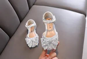 Detalle de zapatos de princesa plateados con lazo de strass y perlas para niñas pequeñas