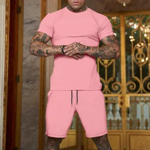 Vista completa di un set t-shirt e pantaloncini rosa da uomo su un modello di fitness tatuato