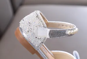 Primer plano de brillantes diamantes de imitación y perlas en zapatos de princesa plata