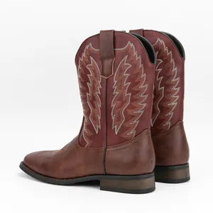Detalle de botas de vaquero occidentales con bordado de alas blancas y acabado en dos tonos.