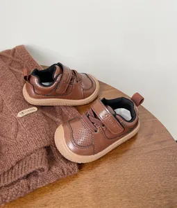 Detail of brown infant walking shoes with soft soles and velcro straps on a cozy background