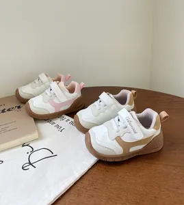 Zapatillas de deporte para bebés con suela blanda en rosa y marrón sobre una mesa