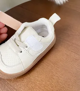 Close-up detail of cream baby walking shoe featuring adjustable Velcro strap and soft sole