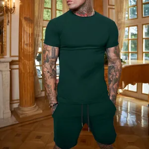 Vista lifestyle completa di un set sportivo da uomo verde scuro con maglietta e pantaloncini