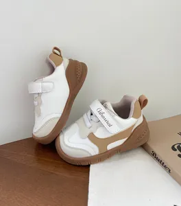 Primer plano de zapatillas para niños pequeños con suelas blandas y diseño blanco y marrón