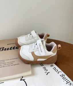 Primer plano de zapatillas para bebé blancas y marrones con suela blanda y velcro