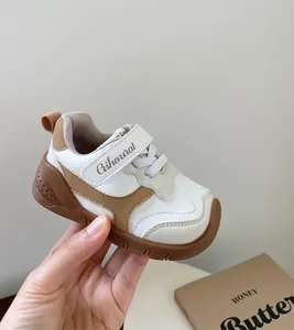 Vista detallada de elegantes zapatillas para niños en marrón y blanco con cierre de velcro