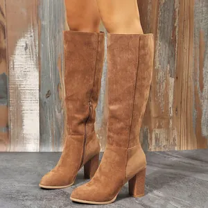 Macro view of tan suede knee-high knight boots with chunky heels and side zipper detail