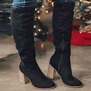 Close-up of black suede knee-high boots with chunky high heel and functional side zipper