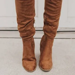 Primer plano de botas mosqueteras de ante marrón con tacón alto y cremallera lateral