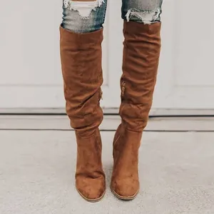 Close-up front view of stylish brown suede block heel boots paired with ripped jeans