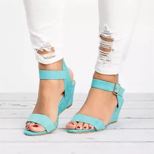 Close-up of stylish teal suede wedge sandals with ankle straps for women's summer fashion.