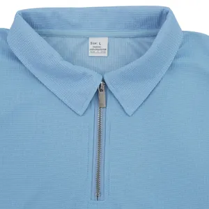 Dettaglio ravvicinato della polo celeste in maglia a nido d'ape con colletto a zip
