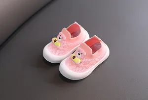 Detalle de zapatos de punto rosas para niños con oso de dibujos animados y malla