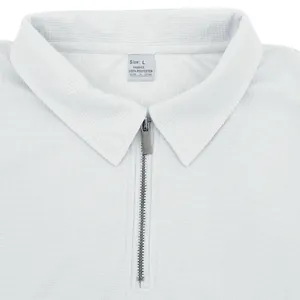 Primer plano detallado de polo de punto gofrado blanco con cremallera y etiqueta