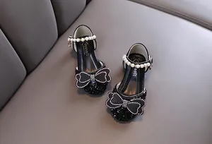 Detail of black girls' princess shoes with pearl strap and rhinestone bow decoration