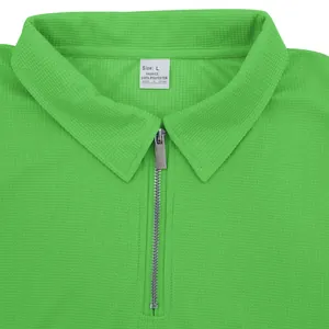 Detalle de un polo verde de punto gofrado con media cremallera plateada y cuello