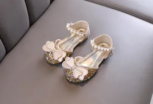 Detailed view of gold sequined princess shoes with pearl straps and elegant bow accents
