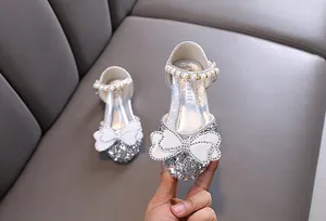 Detailed close-up of sparkling silver princess shoes with pearl strap and rhinestone bow