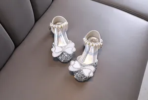 Detailed view of silver sparkly girls princess shoes with pearl strap and rhinestone bow