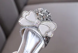 Close-up of silver glitter princess shoe with rhinestone heart bow detail