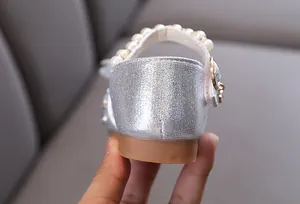 Close-up view of a girl's silver glitter princess shoe heel with pearl strap details
