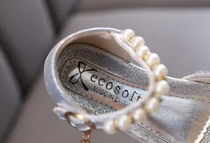 Close-up detail of silver glitter girl princess shoe with elegant pearl strap decoration