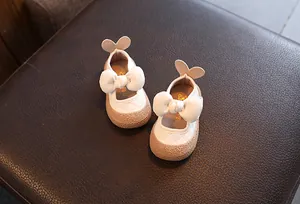 Détail des chaussures blanches pour bébés filles avec un grand nœud et oreilles de lapin
