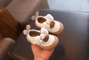 Détail de chaussures de marche matelassées blanches pour bébé fille avec un nœud
